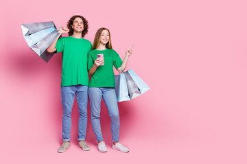 Poster - Full body photo of two friends youngsters pointing finger empty space phone details for shopping online isolated on pink color background