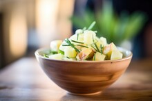 Close-up On Bowl With Rich Green Leek Garnish And Visible Potato Cubes
