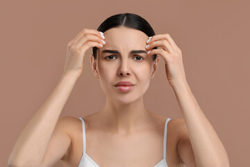 Canvas Print - Woman with dry skin checking her face on beige background