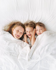 Wall Mural - Happy family - portrait of children and mother in bed. Happy, love and fun at home. Family, childhood.