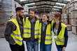 © Halfpoint - Full team of warehouse employees laughing in warehouse, holding each other by shoulders. Team of workers in reflective clothing in modern industrial factory, heavy industry, manufactrury.