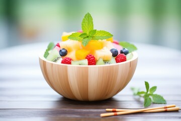 Wall Mural - rainbow fruit salad in a melon bowl with mint leaves