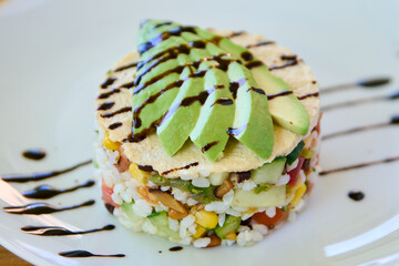 Wall Mural - Avocado tartare with rice and vegetables on a white plate.