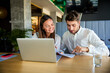 © Westend61 - Smiling businesswoman and businessman discussing over documents in office