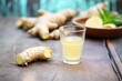 fresh ginger root next to a filled shot glass