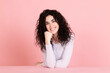 © Westend61 - Smiling young woman sitting at table against pink background