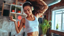 Full Length Of Smiling Young Sporty Woman In Headphones Jumping During Home Aerobics Class