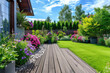The exterior of a back garden patio area with wood decking, flowers garden