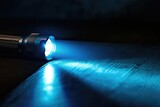 Fototapeta  - Modern LED Flashlight Casting Bright Beam on Dark Wood Table with Copy Space
