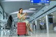 © charlot've  - Asian woman with luggage using phone while waiting for departure at a transportation departure hall