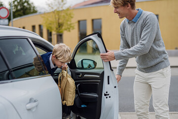 Children getting into the car, father taking them to school and kindergarten before going to work.