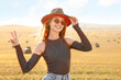 © New Africa - Beautiful happy hippie woman in hat showing peace sign in field