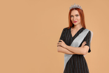 Poster - Beautiful young woman with tiara and ribbon in dress on beige background, space for text. Beauty contest