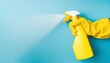 hand in yellow glove with spray on blue background with copy space cleaning concept