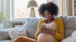 Pregnant woman with smartphone in hands sitting on sofa