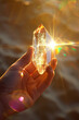 Hand hält einen funkelnden Kristall in der Sonne