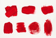Various strokes of red gouache paint on a white sheet of paper