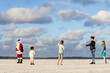 © Austockphoto - family playing beach cricket with child preparing to bowl to a man dressed as santa