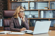 © Liubomir - Elegant senior businesswoman concentrating while working at her home office with a laptop, pen, and notebook.