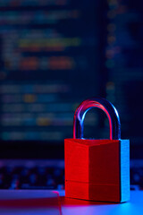 internet security concept. vertical shot of lock over laptop with code in the background lit with bl