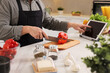 Cooking process. Man using tablet while cutting fresh bell pepper at white marble countertop in kitchen, closeup