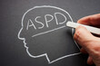 A hand wrote the abbreviation ASPD antisocial personality disorder in chalk.