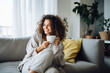 © wolfhound911 - Woman drinking coffee sitting on sofa at home