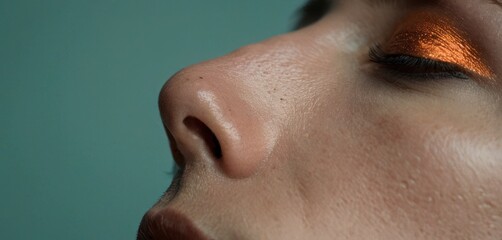 Poster -  a close up of a woman's face with a bright orange eye shadow on her left side of her face and her right eye partially closed to the other half of the other half of her face.