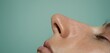© Jevjenijs - a close up of a woman's face with her eyes closed and her nose to the side of her face, with a light blue wall in the background.