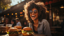 Young Girl Eating Classic Burger With Friends At Cafe In The City. Smiling Beautiful Young Happy Woman Eating Fast Food. 