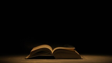 studio shot of old retro hardcover book on dark background in warm light. old vintage book laying op