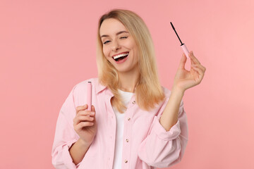 Wall Mural - Beautiful woman with mascara on pink background