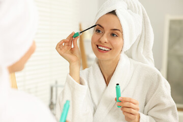 Wall Mural - Beautiful woman applying mascara near mirror in bathroom