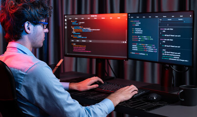 Working IT developer creating online software development information coding on pc screen at back side view, thinking program for latest version application on website at neon modern office. Gusher.