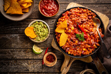 Mexican Hot Chili Con Carne In A Pan With Tortilla Chips On Dark Background, Top View