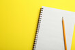 © New Africa - Notebook and pencil on yellow background, top view. Space for text