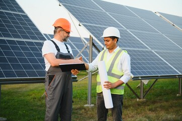 the solar farm(solar panel) with two engineers walk to check the operation of the system