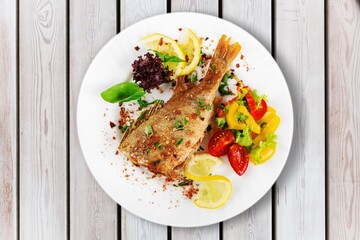 Wall Mural - Fried tasty fish dish with vegetable served on plate