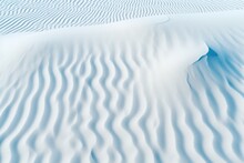  A Large Expanse Of White Sand With Wavy Lines On Top Of It And A Small Patch Of Grass In The Middle Of The Picture.