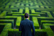 © mila103 - businessman standing at the entrance of a maze, looking at the path ahead