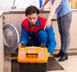 © Elnur - Young male repairman repairing washing machine