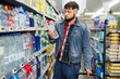 Portrait of focused young glad cheerful positive man purchasing bottled water in grocery store