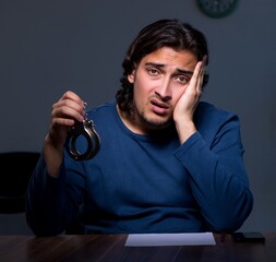 Wall Mural - Young convict man sitting in dark room