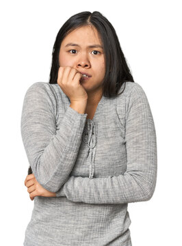 Young chinese woman isolated biting fingernails, nervous and very anxious.