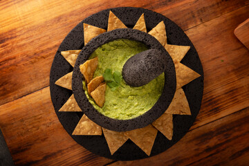 Guacamole. Avocado dip with tortilla chips also called Nachos served in a bowl made with volcanic stone mortar and pestle known as molcajete. Mexican homemade sauce recipe very popular.