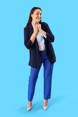Wall Mural - Young woman in stylish suit on blue background