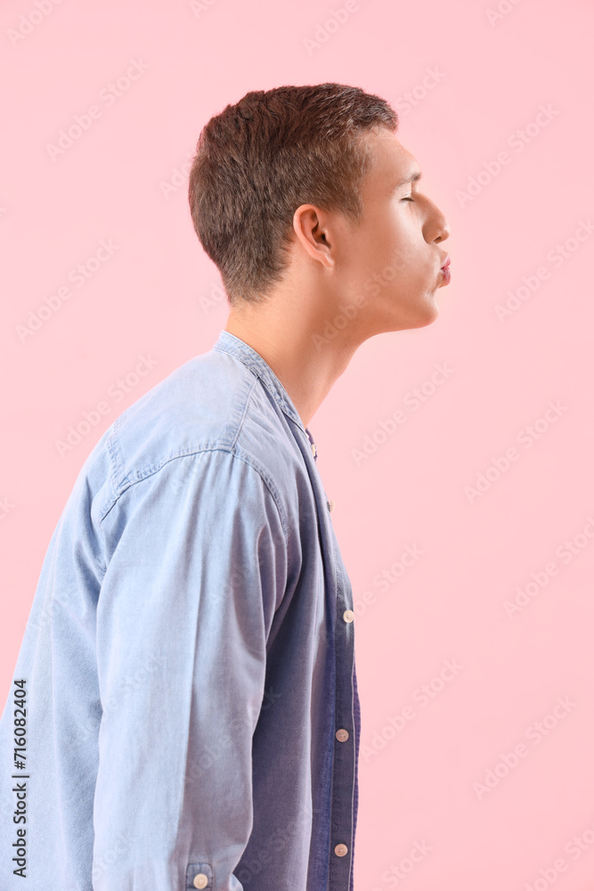 Young man blowing kiss on pink background