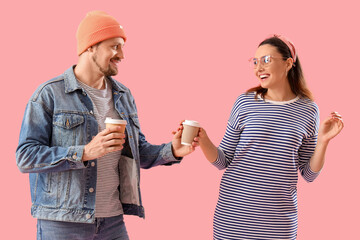 Wall Mural - Happy young couple with cups of coffee on pink background