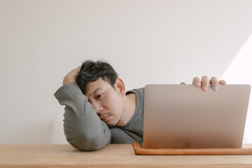 Asian man feeling bored tired and sleepy working with computer.