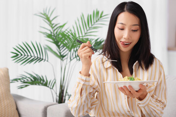 Wall Mural - Young Asian woman with tasty pasta at home